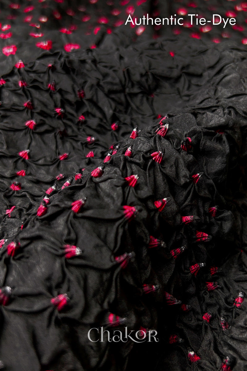 Close-up of Black mulberry silk fabric with Red and white patterns, featuring texture of authentic bandhani patterns.
