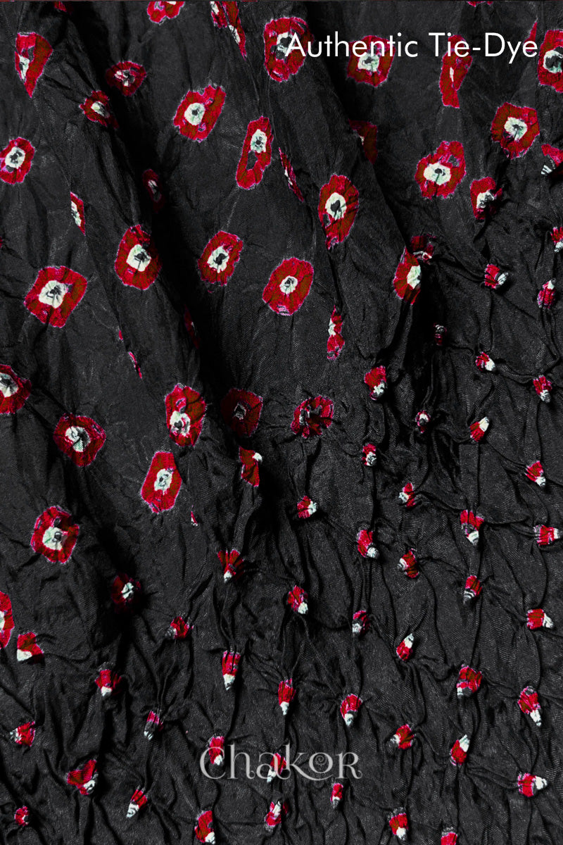 Close-up of Black mulberry silk fabric with Red and white patterns, featuring texture of authentic bandhani patterns.
