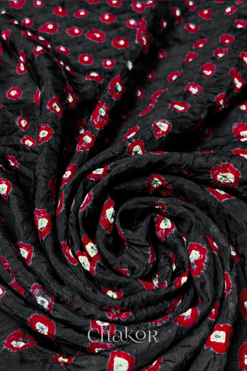 Black Mulberry silk fabric with dual colour Red bandhani dots, arranged in a swirling design  & Chakor brand watermark.
