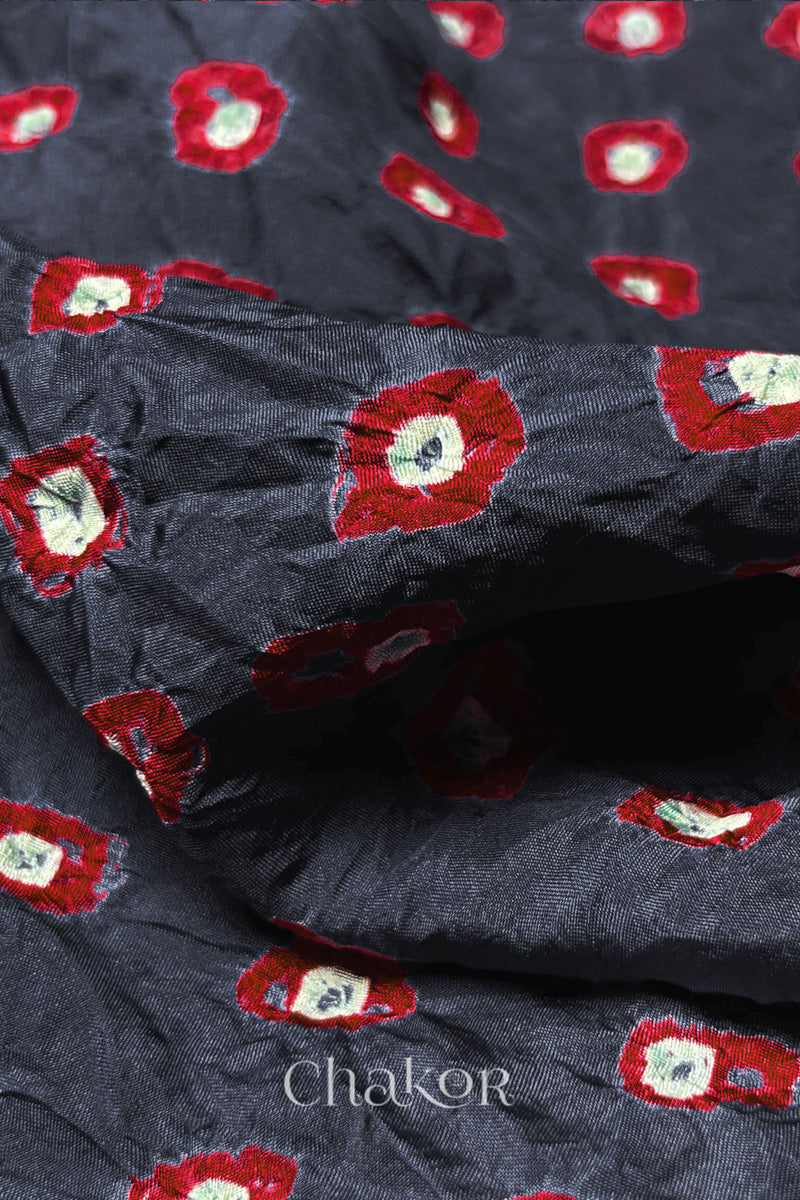 Close-up of Charcoal Grey fabric with Red and white bandhani patterns, featuring texture and sheen of soft mulberry silk fabric.
