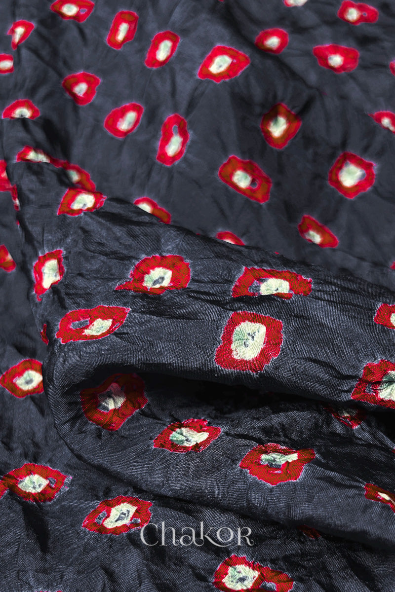 Close-up of Charcoal Grey fabric with Red and white bandhani patterns, featuring texture and sheen of soft mulberry silk fabric.
