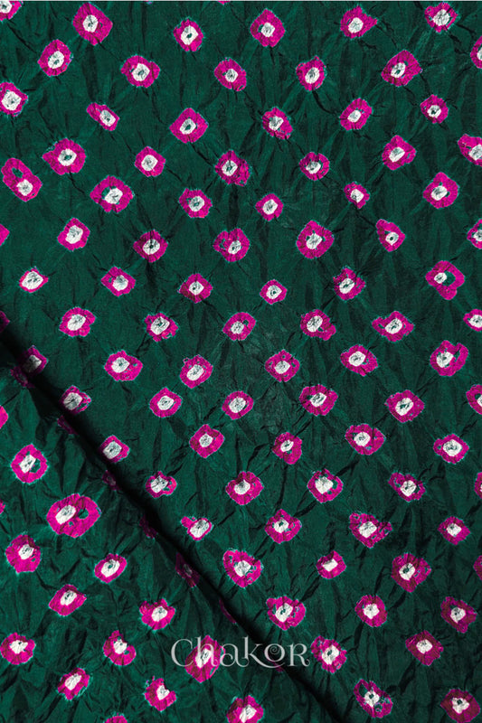 Dark Green Mulberry silk fabric showcasing dual colour Pink bandhani patterns with folded corner and Chakor brand watermark.

