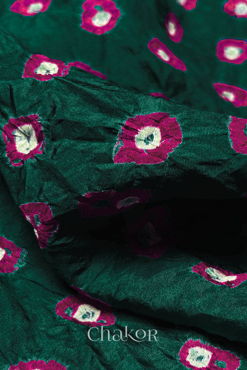 Close-up of Dark Green fabric with Pink and white bandhani patterns, featuring texture and sheen of soft mulberry silk fabric.
