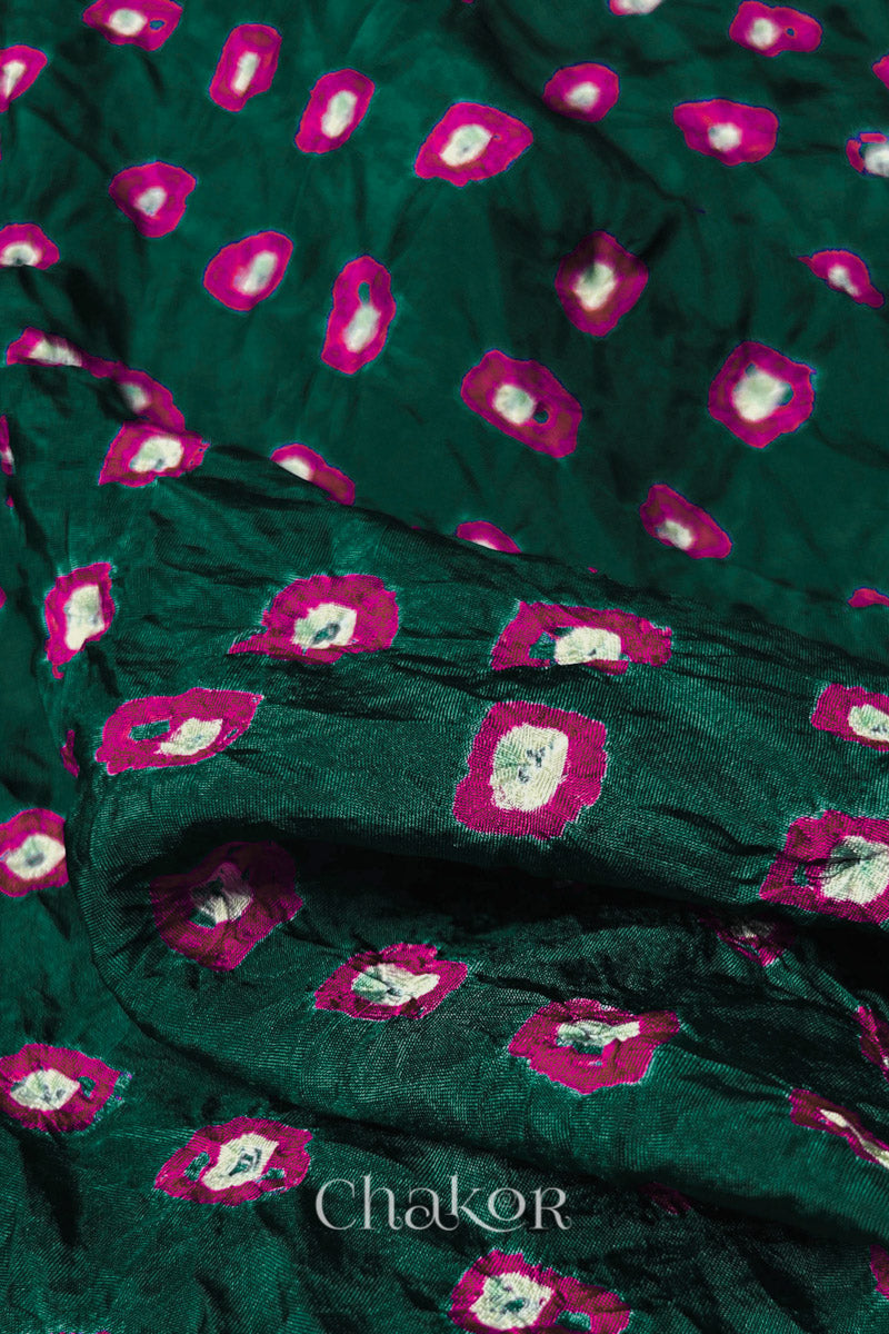 Close-up of Dark Green fabric with Pink and white bandhani patterns, featuring texture and sheen of soft mulberry silk fabric.
