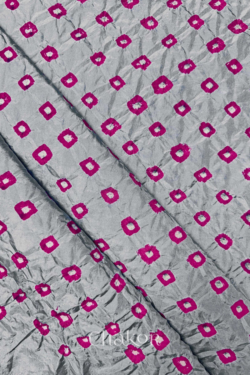 Light Grey Mulberry silk fabric showcasing dual colour Pink bandhani patterns with folds and Chakor brand watermark.
