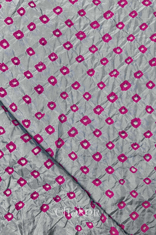 Light Grey Mulberry silk fabric showcasing dual colour Pink bandhani patterns with folded corner and Chakor brand watermark.
