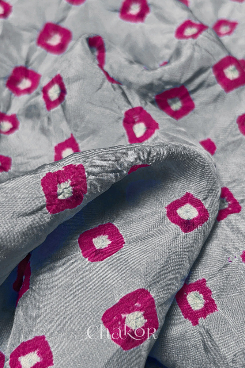 Close-up of Light Grey fabric with Pink and white bandhani patterns, featuring texture and sheen of soft mulberry silk fabric.
