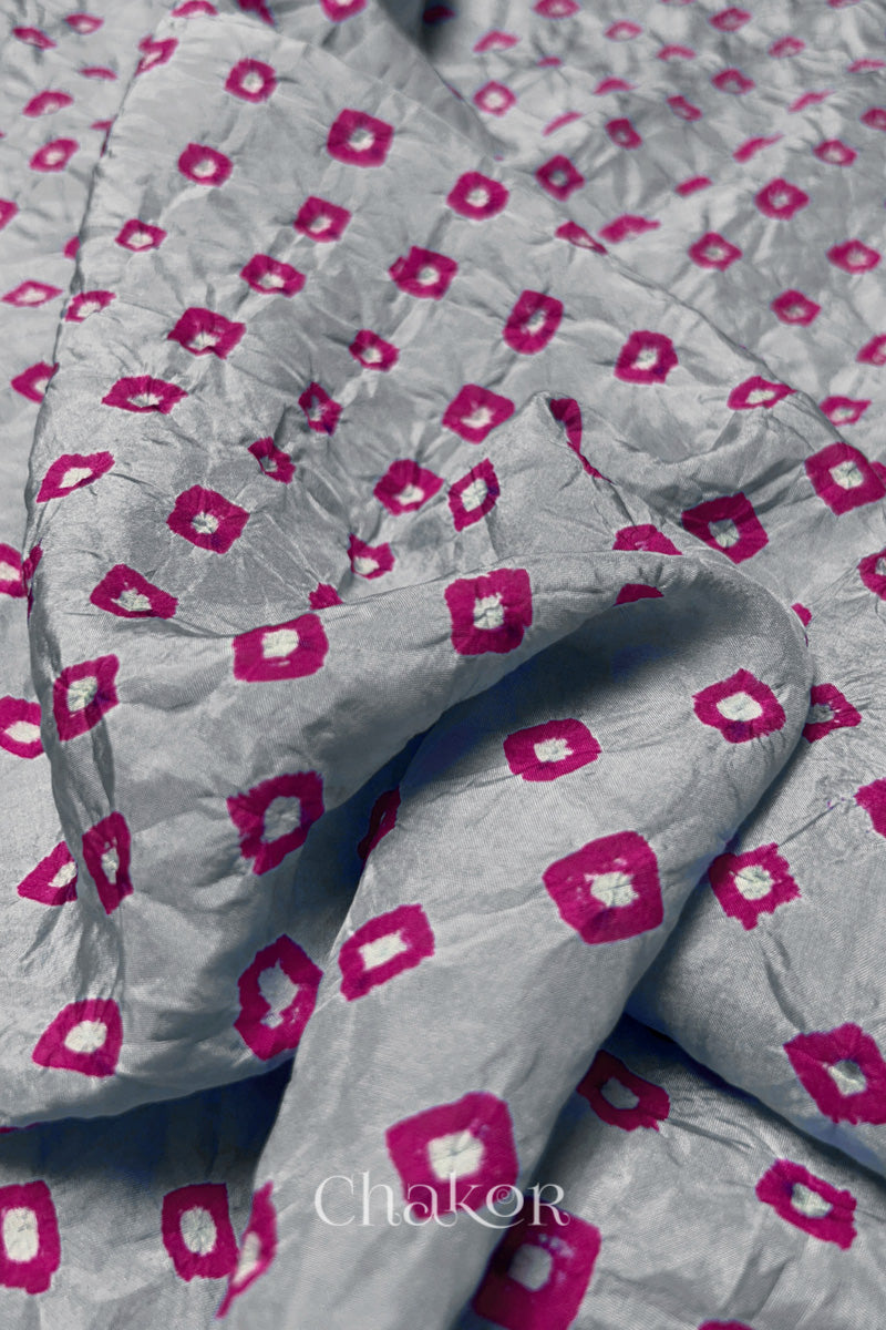 Close-up of Light Grey fabric with Pink and white bandhani patterns, featuring texture and sheen of soft mulberry silk fabric.
