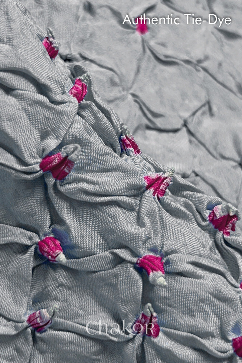 Close-up of Light Grey mulberry silk fabric with Pink and white patterns, featuring texture of authentic bandhani patterns.
