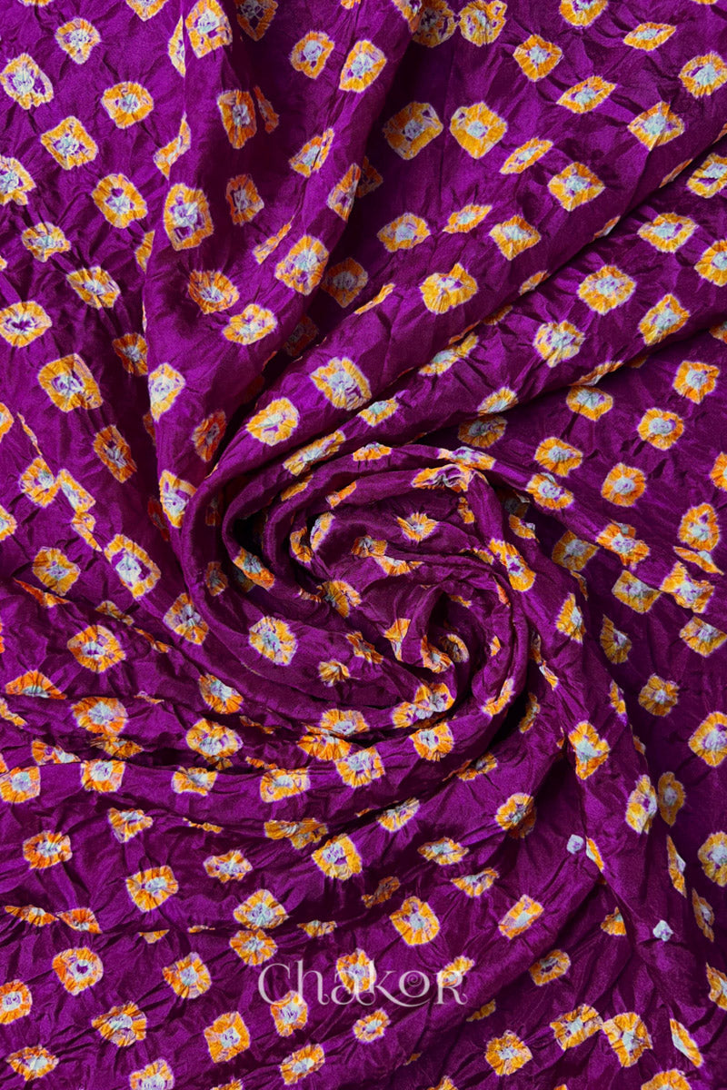 Magenta Mulberry silk fabric with dual colour Yellow bandhani dots, arranged in a swirling design  & Chakor brand watermark.
