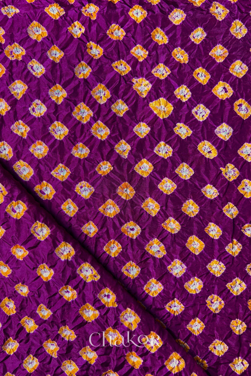 Magenta Mulberry silk fabric showcasing dual colour Yellow bandhani patterns with folded corner and Chakor brand watermark.
