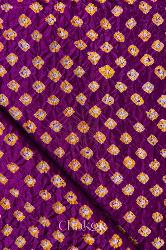 Magenta Mulberry silk fabric showcasing dual colour Yellow bandhani patterns with folded corner and Chakor brand watermark.
