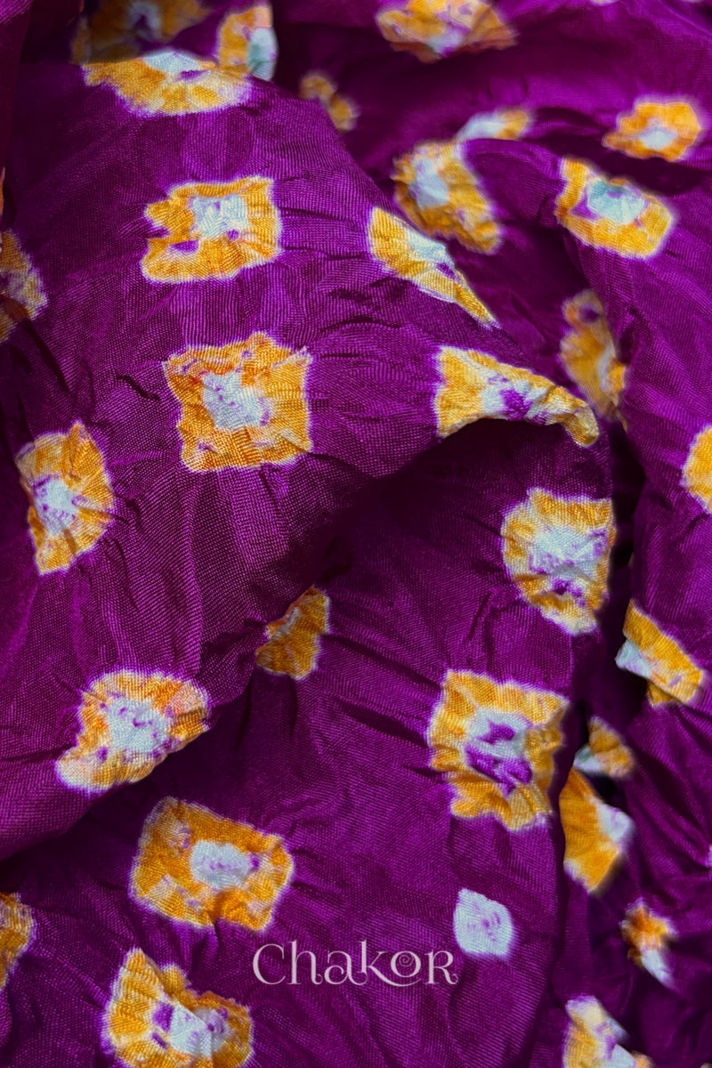 Close-up of Magenta fabric with Yellow and white bandhani patterns, featuring texture and sheen of soft mulberry silk fabric.
