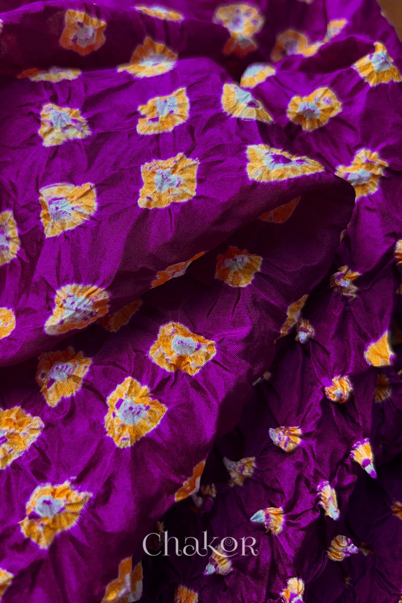 Close-up of Magenta fabric with Yellow and white bandhani patterns, featuring texture and sheen of soft mulberry silk fabric.
