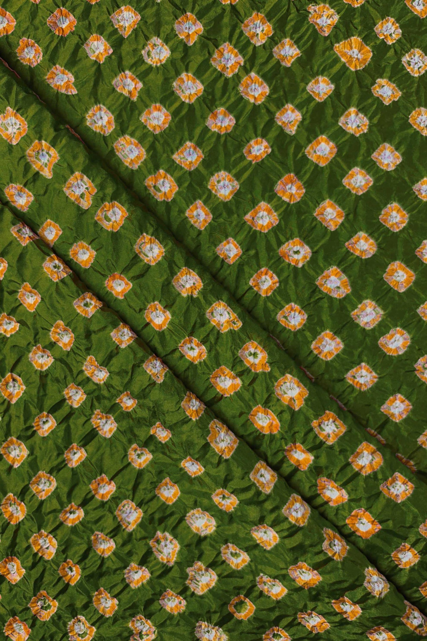 Mehendi Green Mulberry silk fabric showcasing dual colour Yellow bandhani patterns with folds and Chakor brand watermark.
