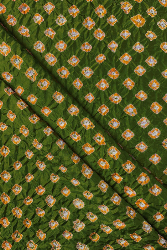 Mehendi Green Mulberry silk fabric showcasing dual colour Yellow bandhani patterns with folds and Chakor brand watermark.
