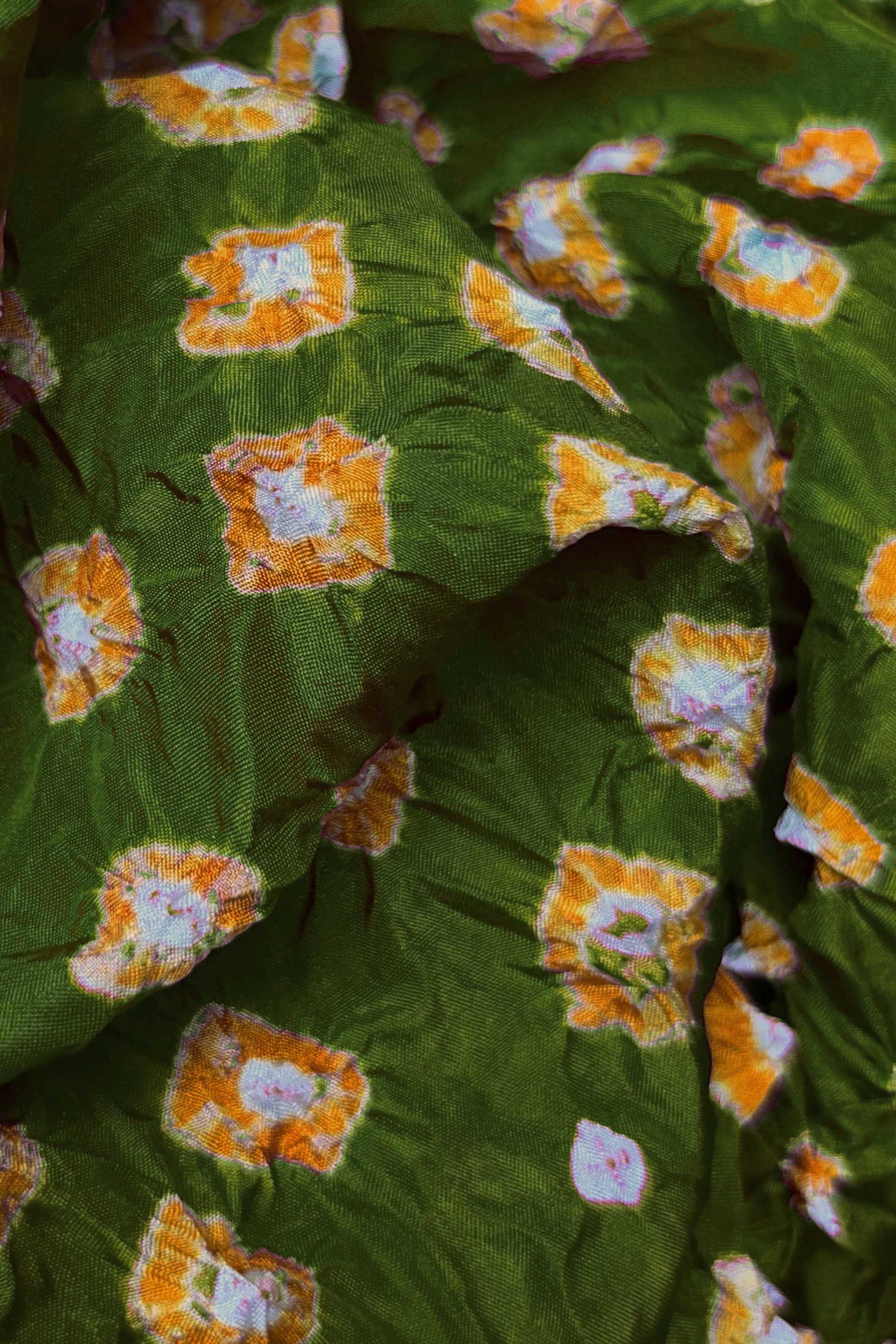 Close-up of Mehendi Green fabric with Yellow and white bandhani patterns, featuring texture and sheen of soft mulberry silk fabric.
