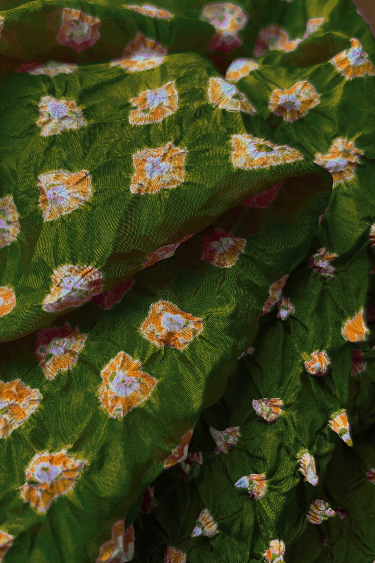 Close-up of Mehendi Green fabric with Yellow and white bandhani patterns, featuring texture and sheen of soft mulberry silk fabric.
