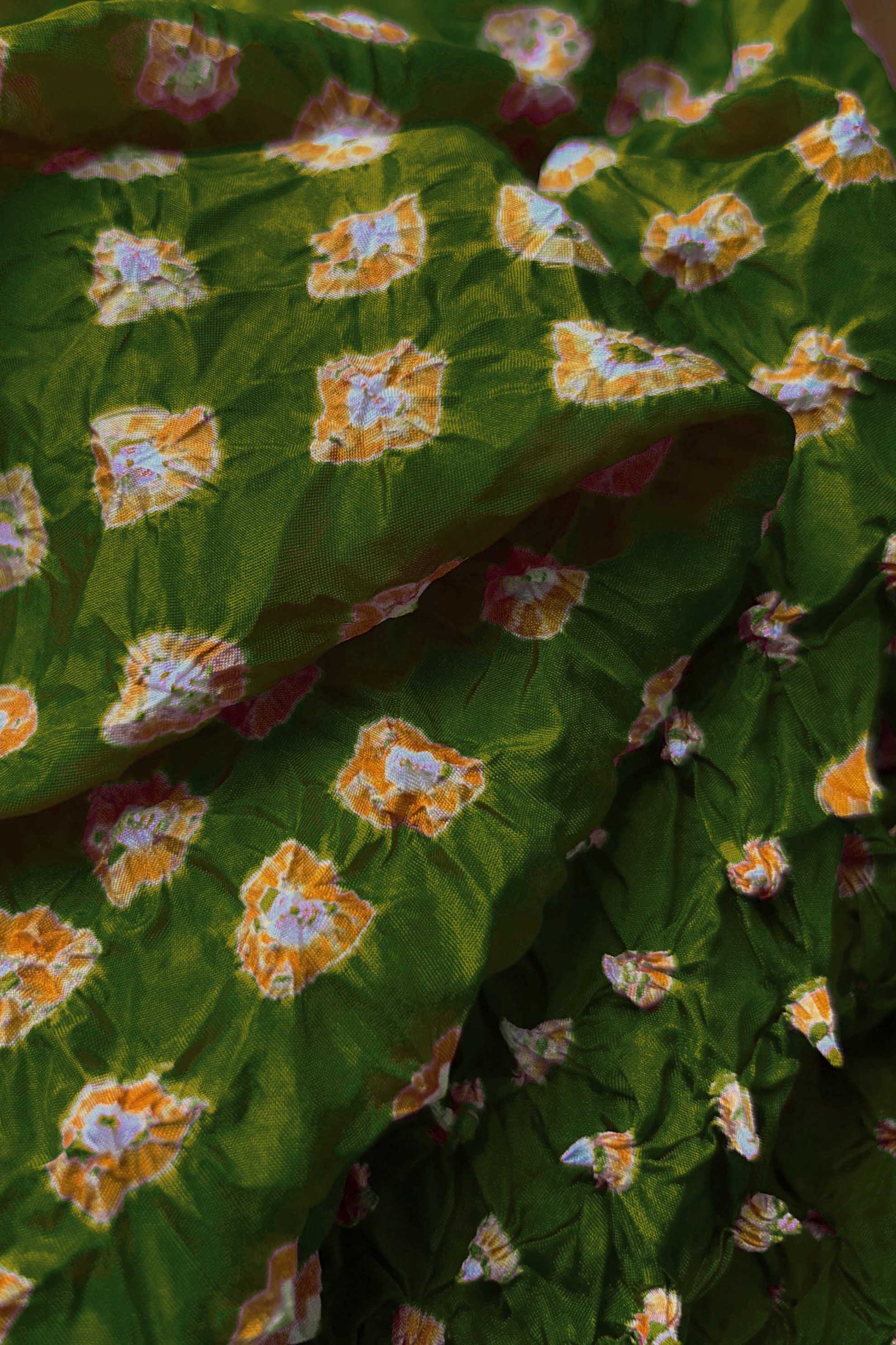 Close-up of Mehendi Green fabric with Yellow and white bandhani patterns, featuring texture and sheen of soft mulberry silk fabric.

