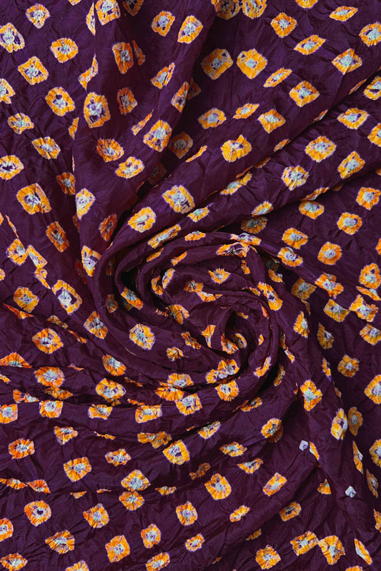 Maroon Mulberry silk fabric with dual colour Yellow bandhani dots, arranged in a swirling design  & Chakor brand watermark.
