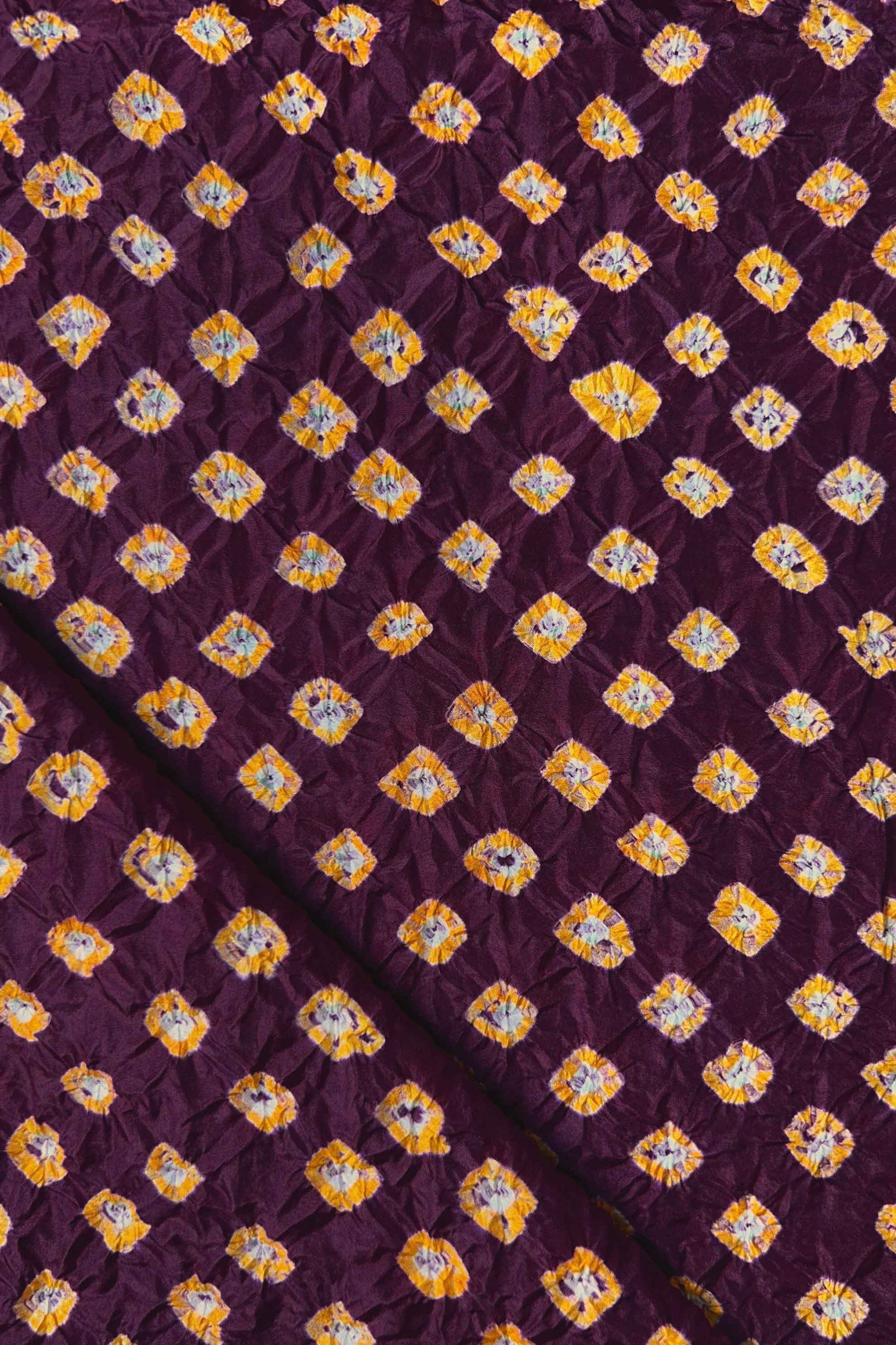 Maroon Mulberry silk fabric showcasing dual colour Yellow bandhani patterns with folded corner and Chakor brand watermark.

