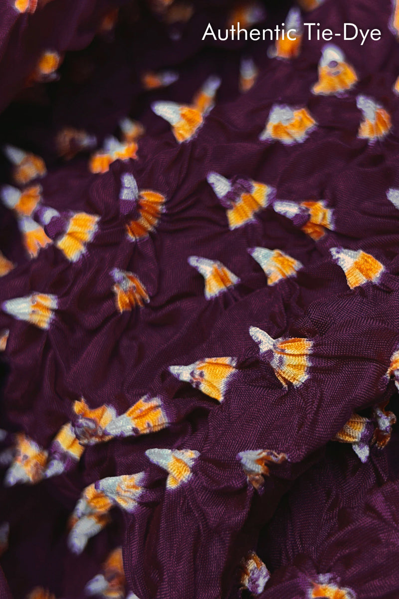Close-up of Maroon mulberry silk fabric with Yellow and white patterns, featuring texture of authentic bandhani patterns.
