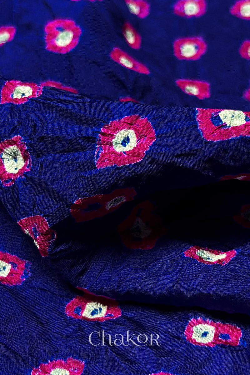 Close-up of Navy fabric with Pink and white bandhani patterns, featuring texture and sheen of soft mulberry silk fabric.
