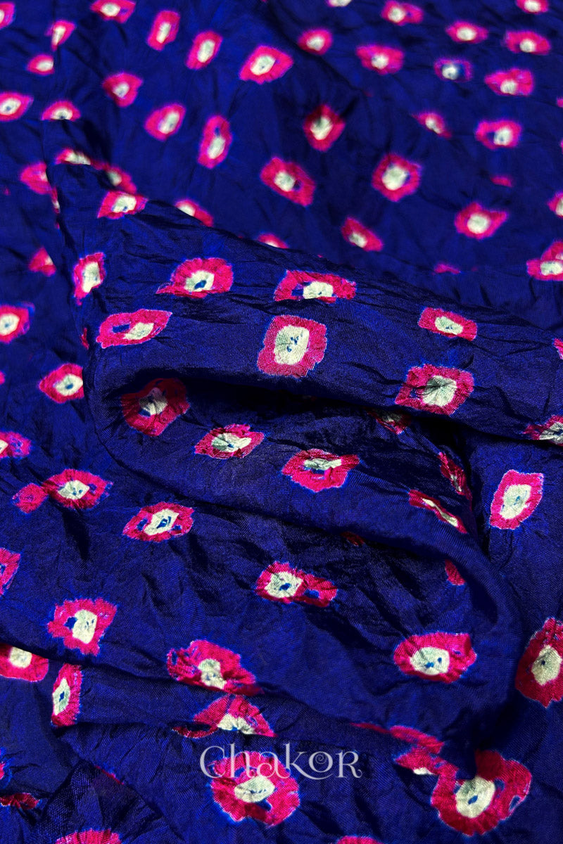 Close-up of Navy fabric with Pink and white bandhani patterns, featuring texture and sheen of soft mulberry silk fabric.

