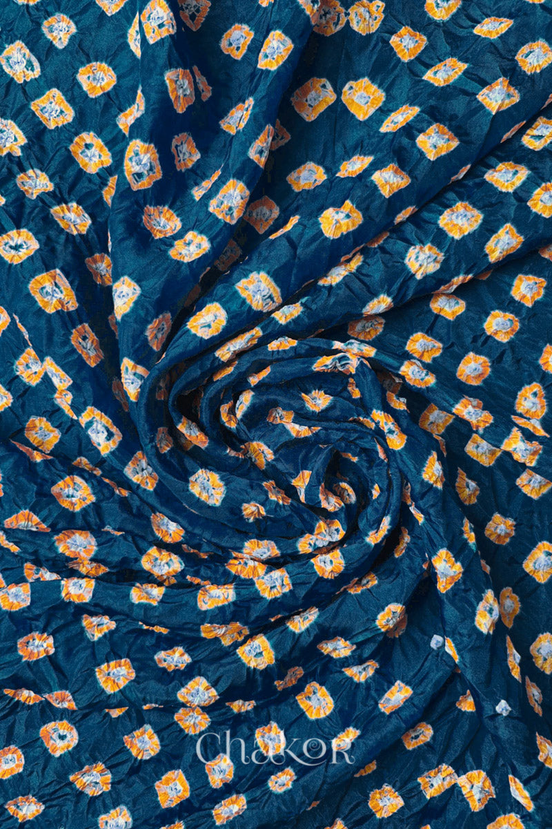 Deep Indigo Mulberry silk fabric with dual colour Yellow bandhani dots, arranged in a swirling design  & Chakor brand watermark.
