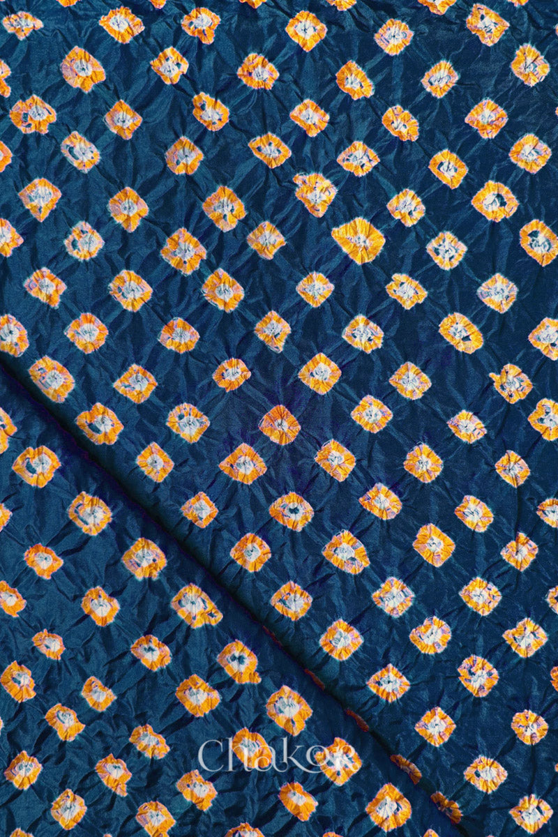 Deep Indigo Mulberry silk fabric showcasing dual colour Yellow bandhani patterns with folded corner and Chakor brand watermark.
