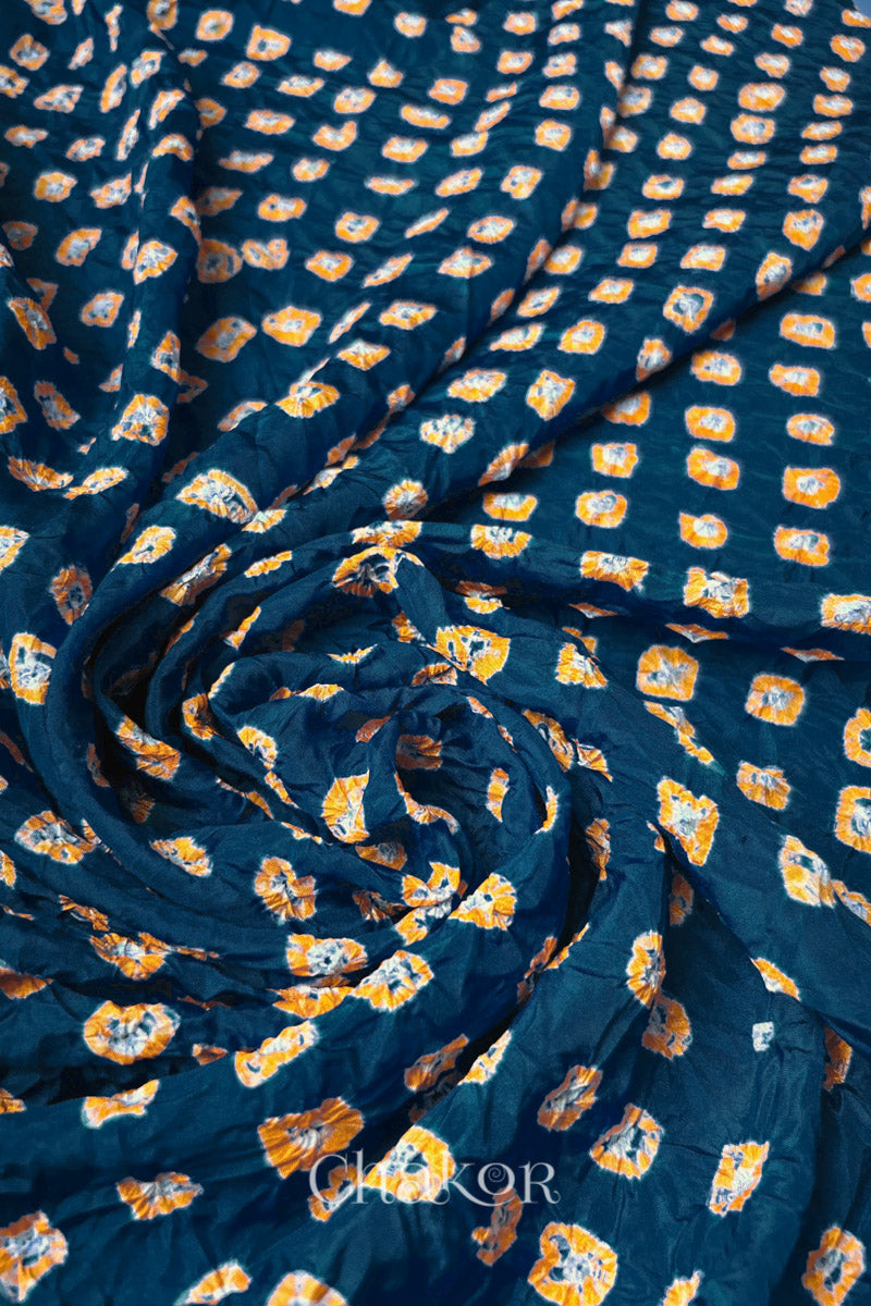 Deep Indigo Mulberry silk fabric with dual colour Yellow bandhani dots, arranged in a swirling design  & Chakor brand watermark.
