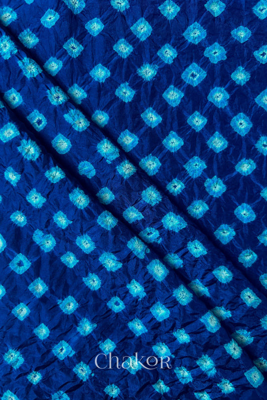 Navy Mulberry silk fabric showcasing dual colour Turquoise Blue bandhani patterns with folds and Chakor brand watermark.
