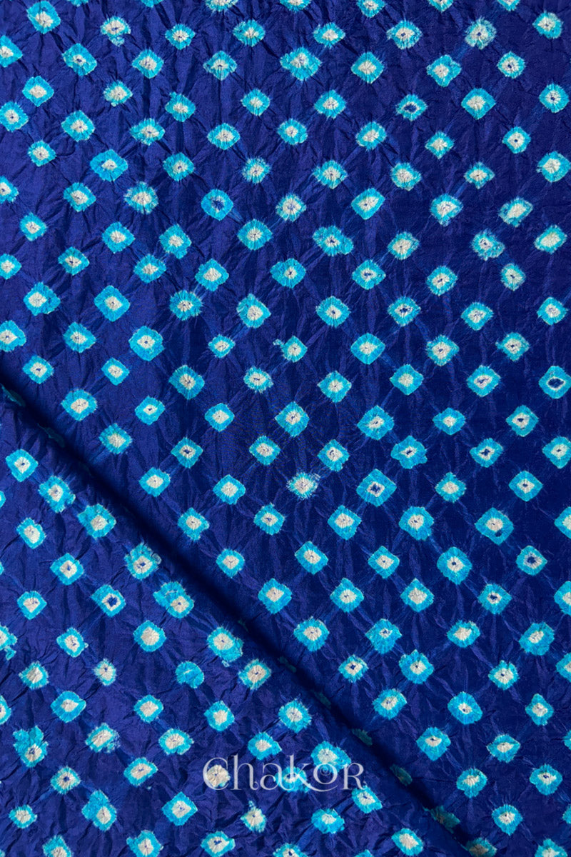 Navy Mulberry silk fabric showcasing dual colour Turquoise Blue bandhani patterns with folded corner and Chakor brand watermark.
