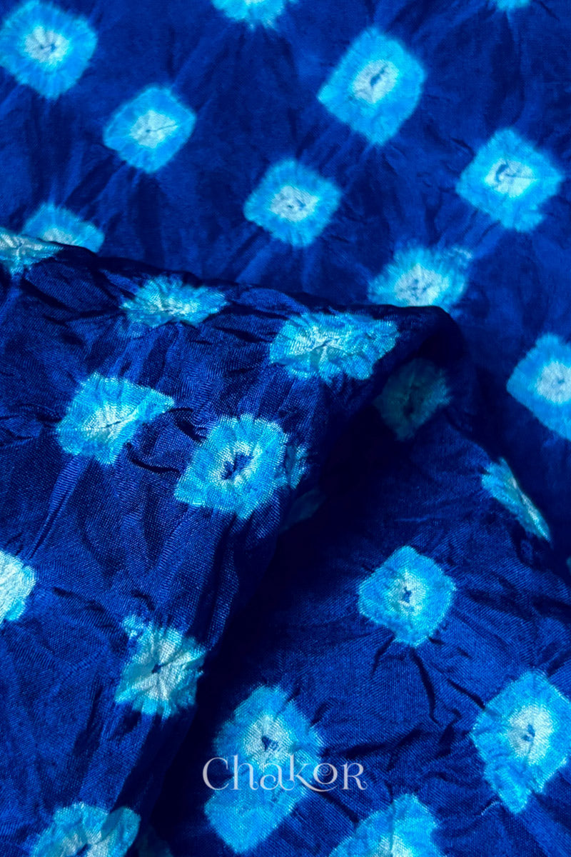 Close-up of Navy fabric with Turquoise Blue and white bandhani patterns, featuring texture and sheen of soft mulberry silk fabric.
