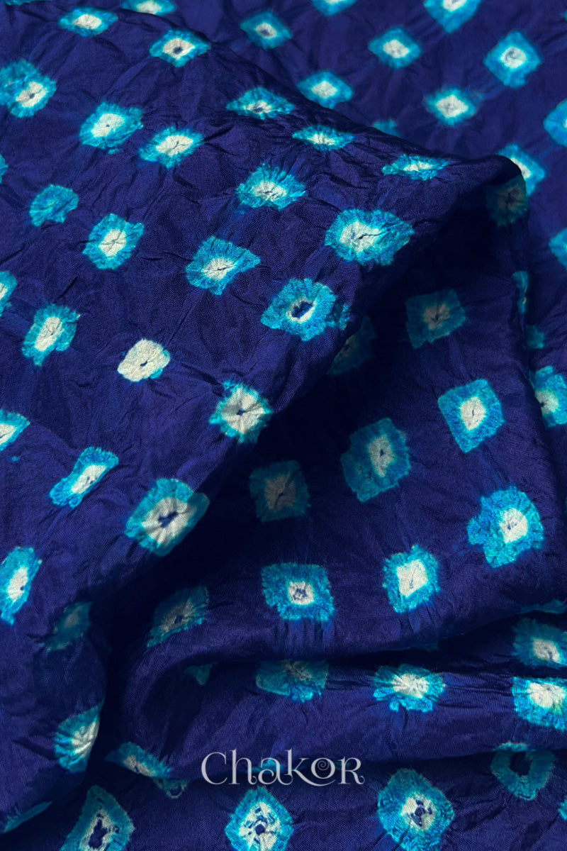 Close-up of Navy fabric with Turquoise Blue and white bandhani patterns, featuring texture and sheen of soft mulberry silk fabric.
