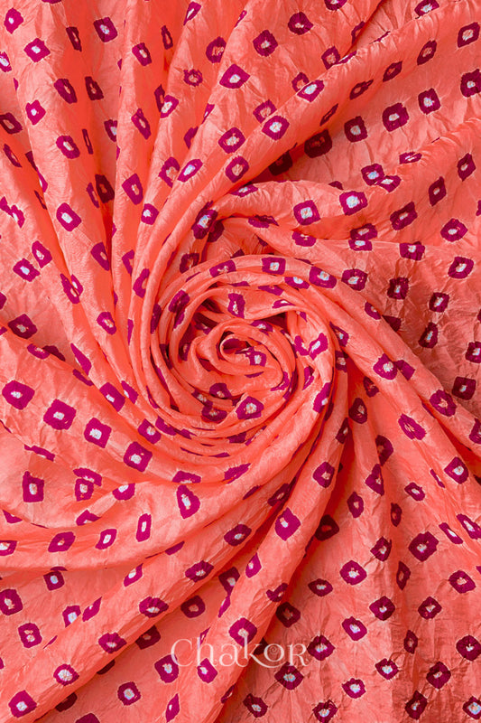 Peach Mulberry silk fabric with dual colour Pink bandhani dots, arranged in a swirling design  & Chakor brand watermark.
