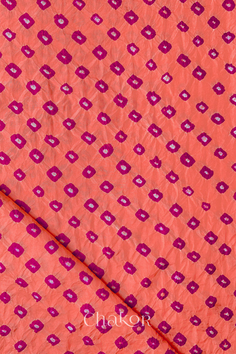 Peach Mulberry silk fabric showcasing dual colour Pink bandhani patterns with folded corner and Chakor brand watermark.
