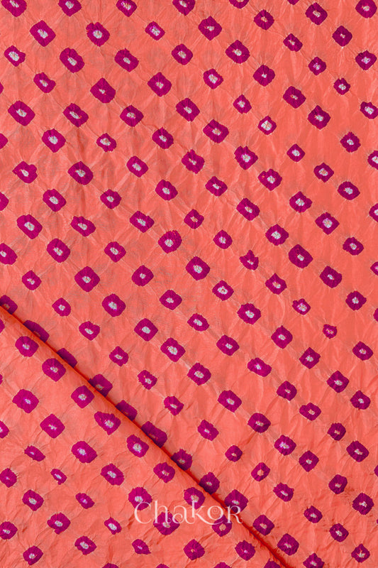 Peach Mulberry silk fabric showcasing dual colour Pink bandhani patterns with folded corner and Chakor brand watermark.
