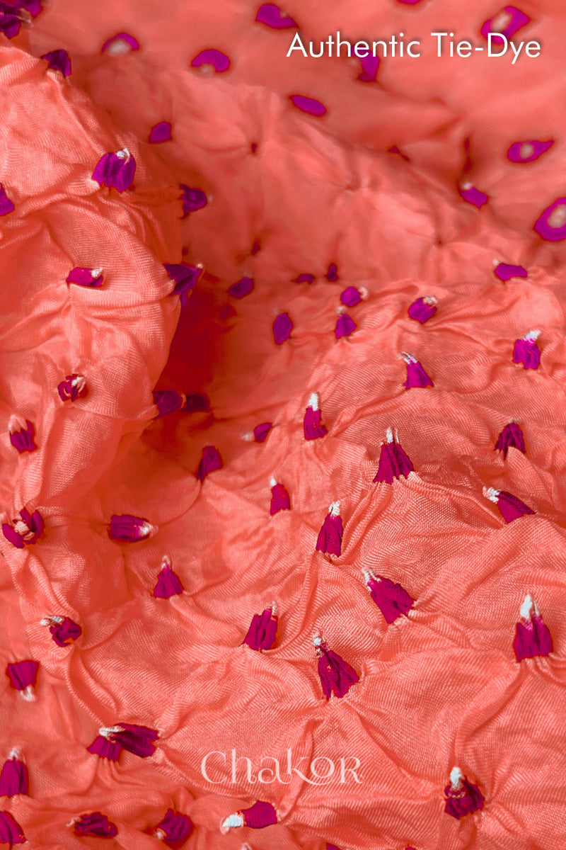 Close-up of Peach mulberry silk fabric with Pink and white patterns, featuring texture of authentic bandhani patterns.
