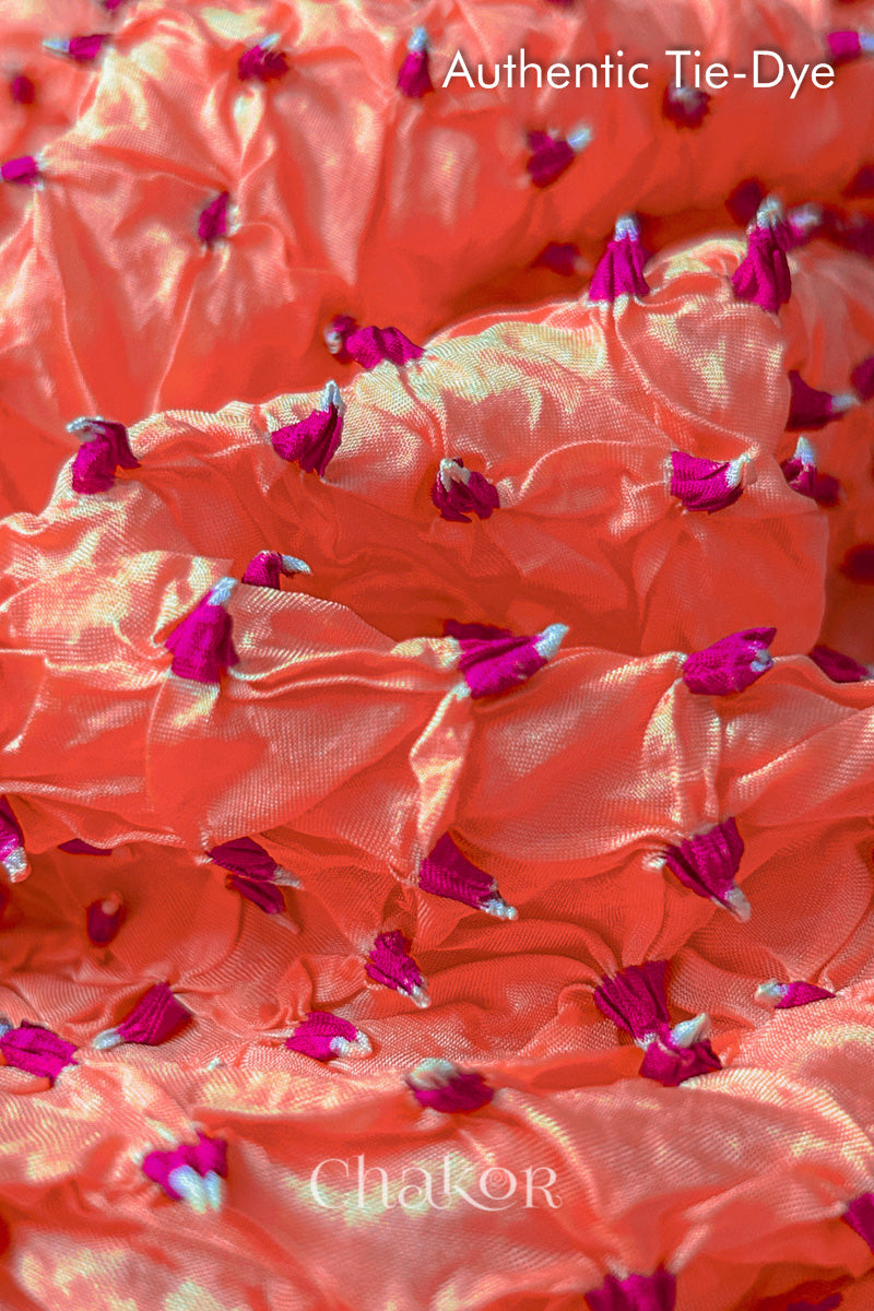 Close-up of Peach mulberry silk fabric with Pink and white patterns, featuring texture of authentic bandhani patterns.
