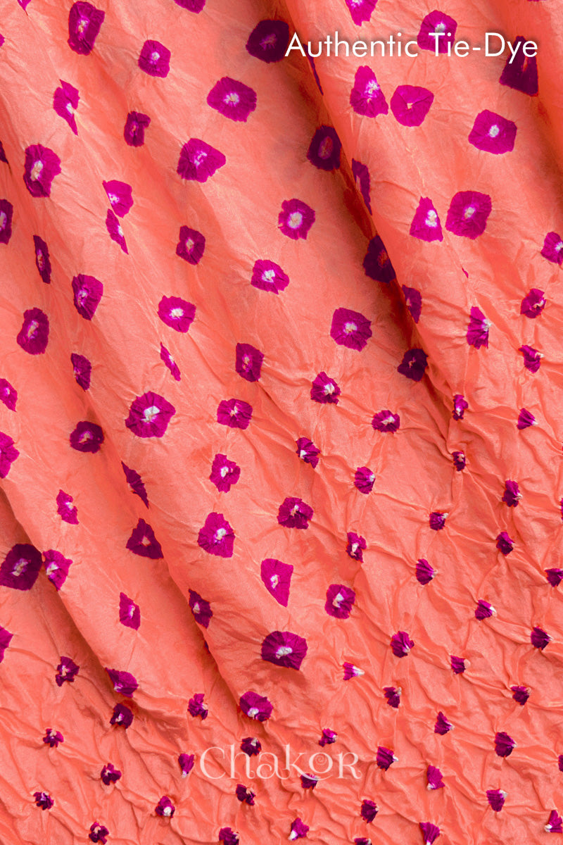 Close-up of Peach mulberry silk fabric with Pink and white patterns, featuring texture of authentic bandhani patterns.
