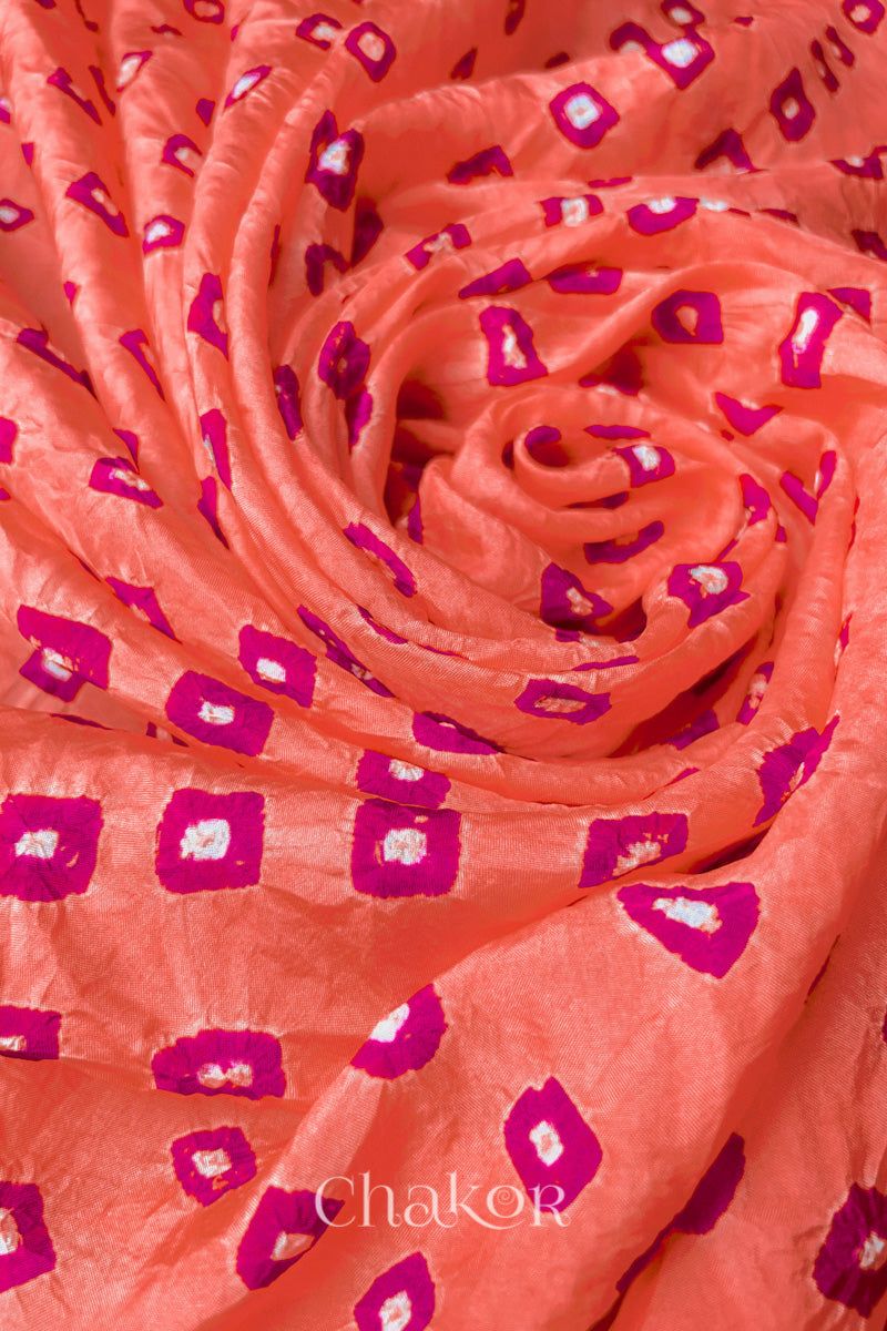 Peach Mulberry silk fabric with dual colour Pink bandhani dots, arranged in a swirling design  & Chakor brand watermark.

