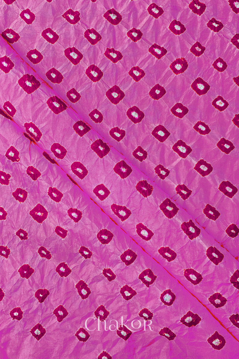 Light Pink Mulberry silk fabric showcasing dual colour Pink bandhani patterns with folds and Chakor brand watermark.
