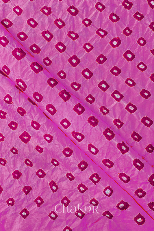 Light Pink Mulberry silk fabric showcasing dual colour Pink bandhani patterns with folds and Chakor brand watermark.
