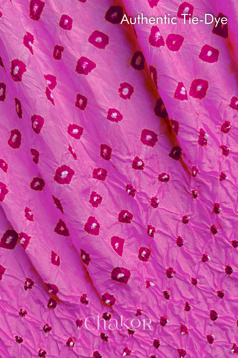 Close-up of Light Pink mulberry silk fabric with Pink and white patterns, featuring texture of authentic bandhani patterns.
