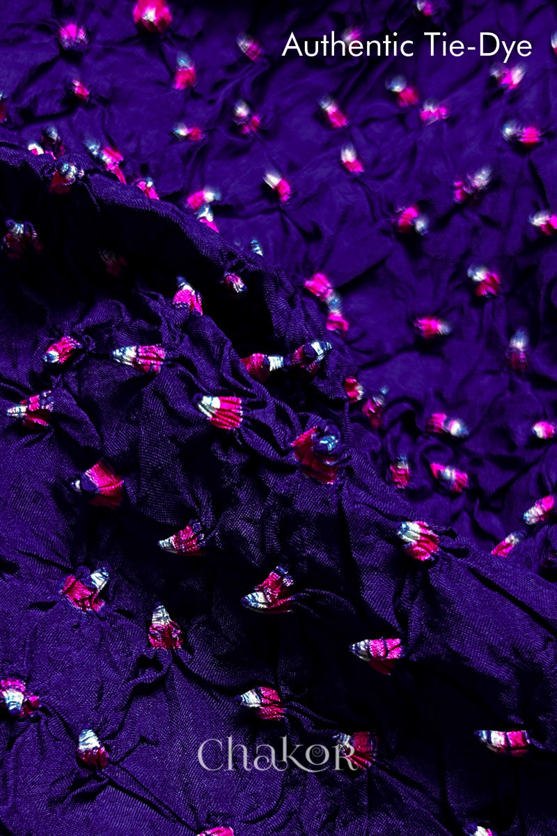 Close-up of Purple mulberry silk fabric with Pink and white patterns, featuring texture of authentic bandhani patterns.
