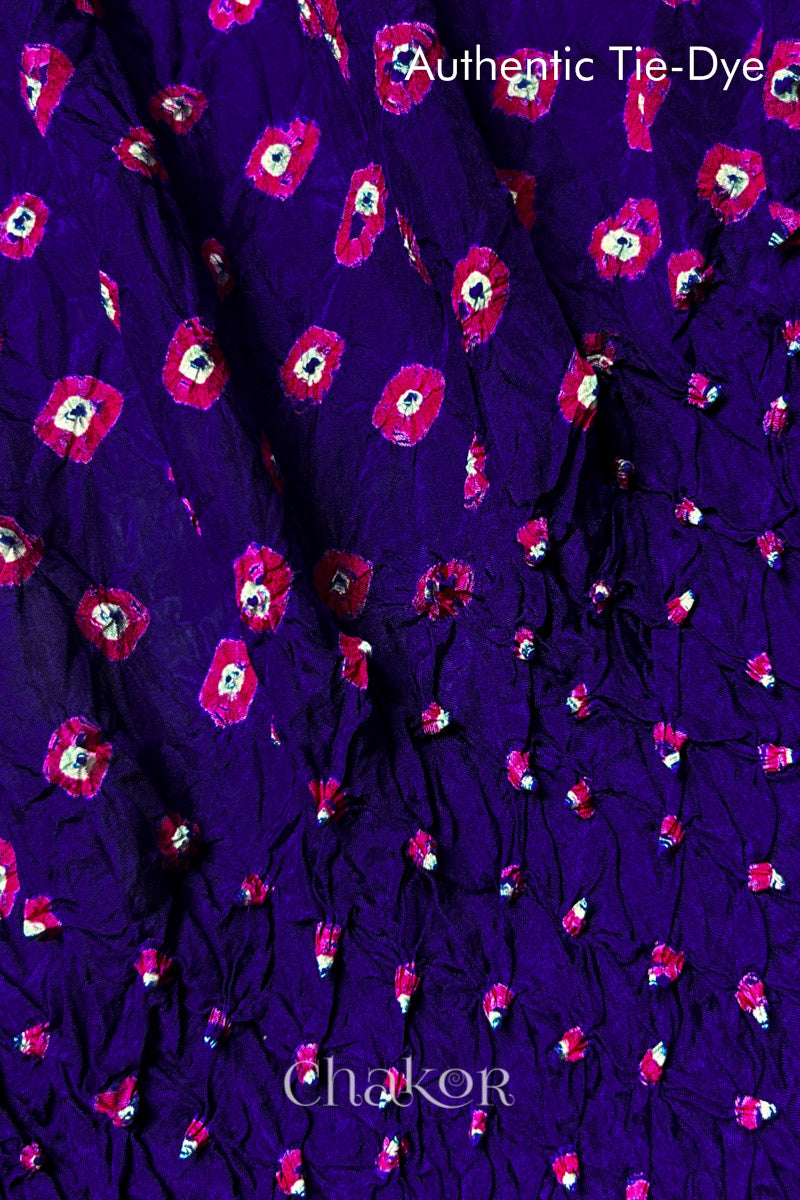 Close-up of Purple mulberry silk fabric with Pink and white patterns, featuring texture of authentic bandhani patterns.
