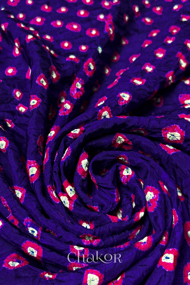 Purple Mulberry silk fabric with dual colour Pink bandhani dots, arranged in a swirling design  & Chakor brand watermark.
