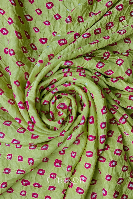 Pista Green Mulberry silk fabric with dual colour Pink bandhani dots, arranged in a swirling design  & Chakor brand watermark.
