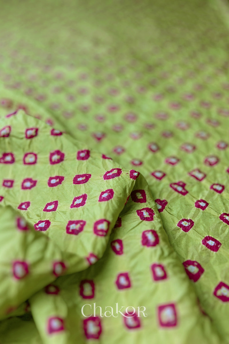 Close-up of Pista Green fabric with Pink and white bandhani patterns, featuring texture and sheen of soft mulberry silk fabric.

